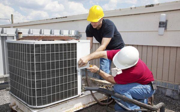 Một người đang thực hiện vệ sinh và bảo dưỡng điều hòa âm trần nối ống gió, bao gồm việc làm sạch lưới lọc và kiểm tra ống dẫn.