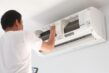 Kỹ thuật viên đang kiểm tra và siết chặt các ốc vít của dàn nóng điều hòa kêu to, minh họa lỗi lắp đặt sai.