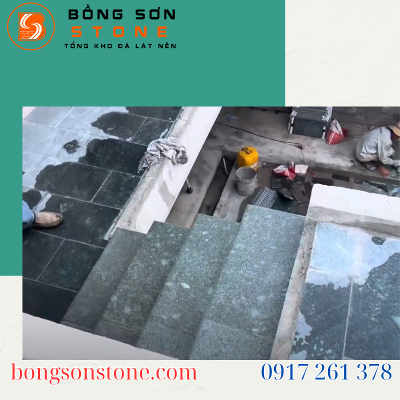 Một người thợ đang tỉ mỉ ốp từng tấm đá lát cầu thang, sử dụng búa cao su để căn chỉnh, trong không gian nhà đang hoàn thiện.